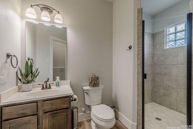 bathroom featuring toilet, a stall shower, wood finished floors, and vanity