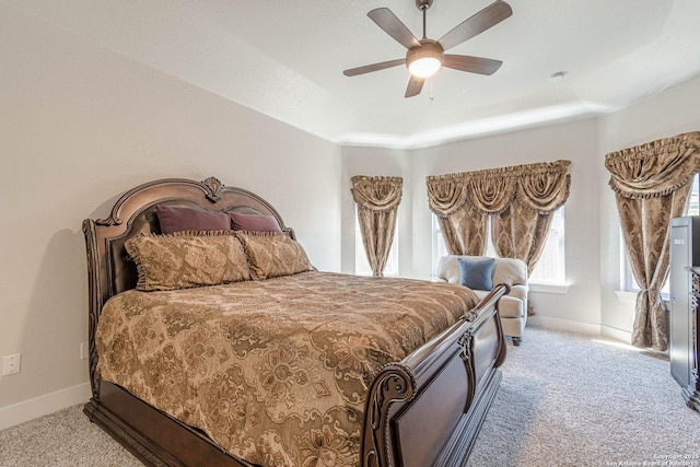 bedroom featuring ceiling fan, carpet floors, a tray ceiling, and baseboards