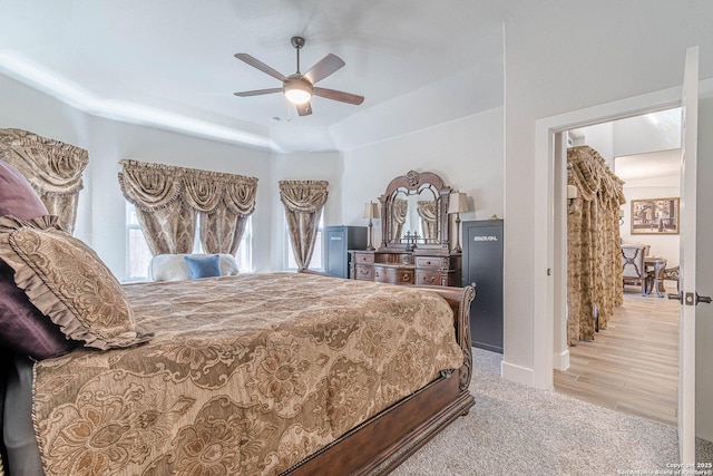 bedroom with carpet floors, ceiling fan, and a tray ceiling