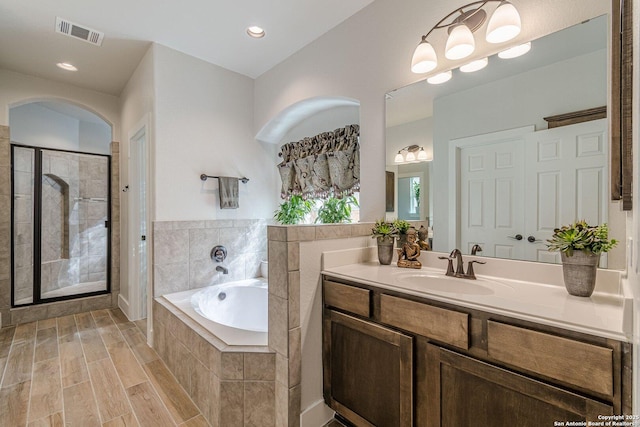 bathroom featuring a garden tub, visible vents, a shower stall, vanity, and wood finished floors