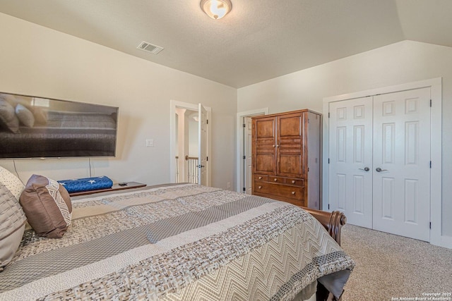 carpeted bedroom featuring a textured ceiling, visible vents, vaulted ceiling, and a closet