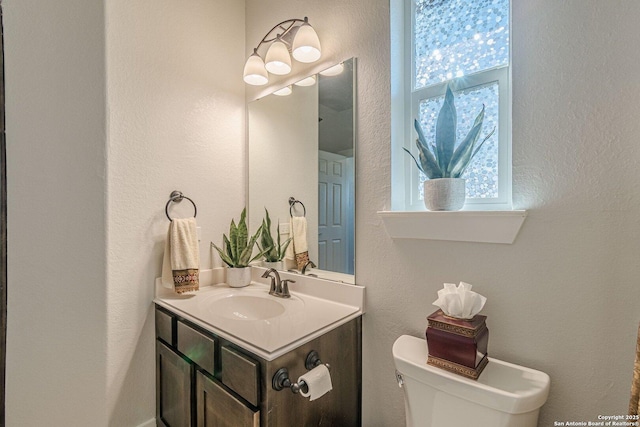 bathroom featuring a textured wall, vanity, and toilet