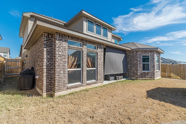 back of property with a yard, fence, and brick siding