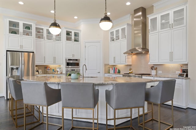 kitchen with white cabinets, wall chimney exhaust hood, dark wood-type flooring, stainless steel appliances, and a sink