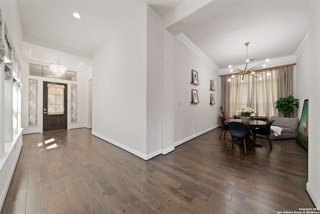 entryway with ornamental molding, a notable chandelier, and wood finished floors