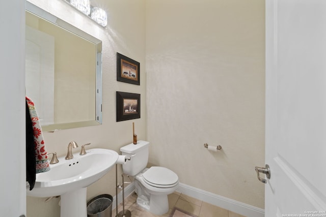 half bath featuring baseboards, a sink, toilet, and tile patterned floors