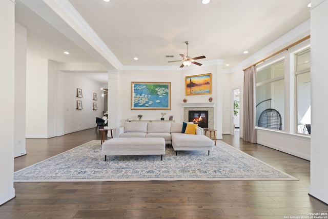 living room with ornamental molding, a glass covered fireplace, and wood finished floors