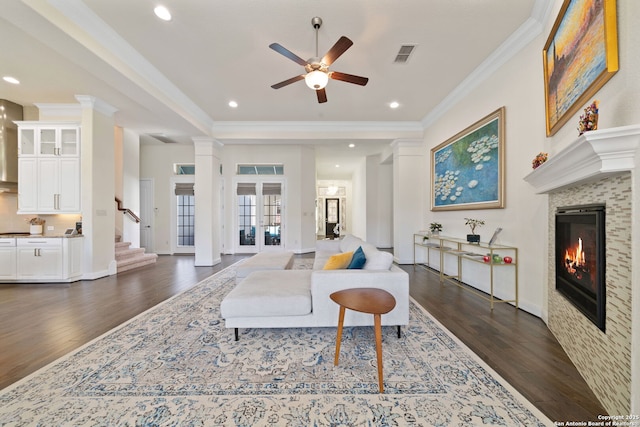 living room with dark wood-type flooring, a tile fireplace, ornamental molding, and stairway