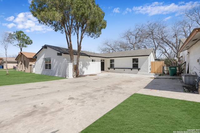 exterior space with a front yard, fence, concrete driveway, and brick siding