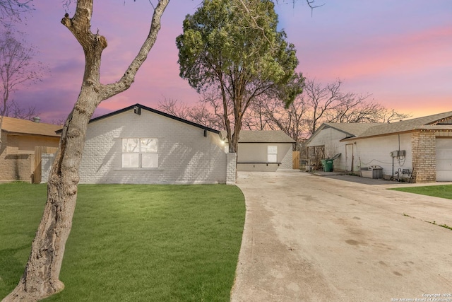 mid-century inspired home featuring a front lawn, concrete driveway, and brick siding