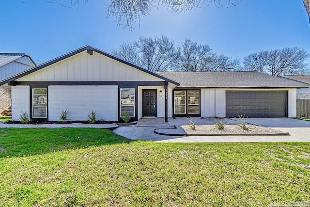 view of front of house featuring an attached garage, driveway, brick siding, and a front yard