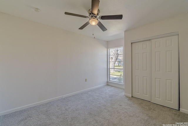 unfurnished bedroom featuring carpet floors, a closet, baseboards, and a ceiling fan