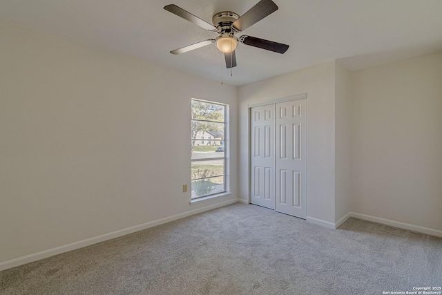 unfurnished bedroom featuring light carpet, ceiling fan, baseboards, and a closet