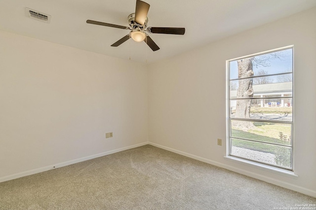 spare room with baseboards, ceiling fan, visible vents, and light colored carpet