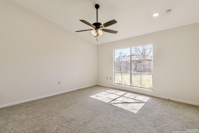 carpeted empty room featuring baseboards, vaulted ceiling, and a ceiling fan