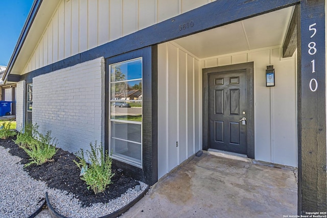 doorway to property with brick siding and board and batten siding