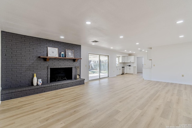 unfurnished living room featuring a brick fireplace, light wood-style flooring, visible vents, and recessed lighting