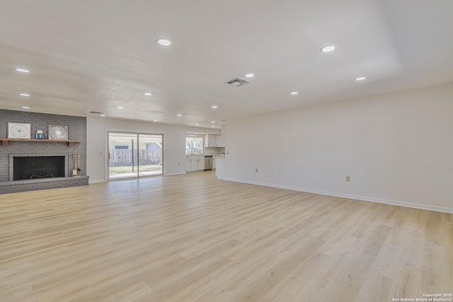 unfurnished living room featuring a brick fireplace, visible vents, and light wood-style flooring