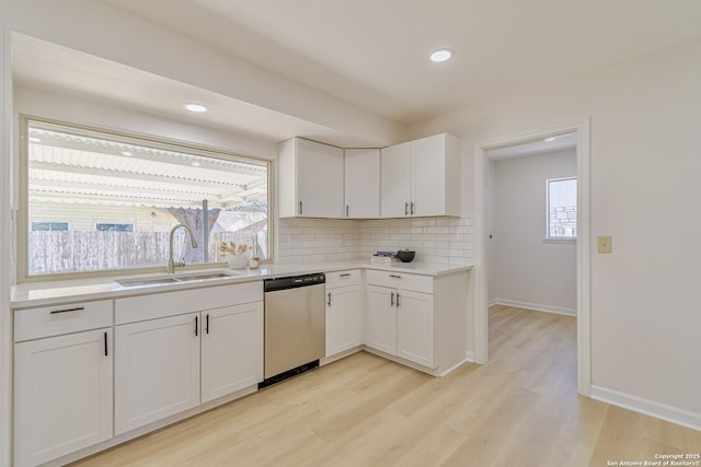 kitchen with a sink, white cabinetry, light countertops, stainless steel dishwasher, and decorative backsplash