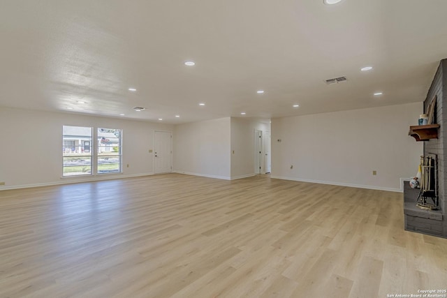 unfurnished living room with light wood-type flooring, baseboards, a fireplace, and visible vents