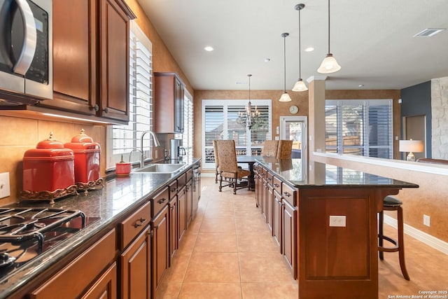 kitchen featuring a breakfast bar, a center island, stainless steel microwave, a sink, and gas cooktop