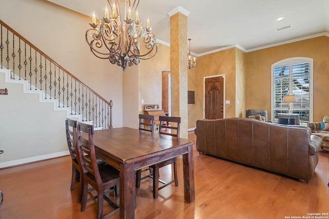 dining space with visible vents, light wood-style flooring, stairs, crown molding, and a notable chandelier