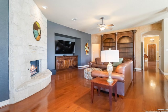 living area featuring visible vents, a fireplace, arched walkways, and wood finished floors