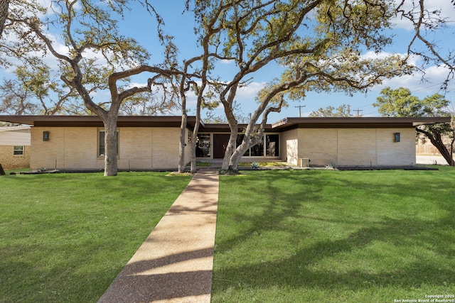 mid-century inspired home with a front yard, brick siding, and central AC