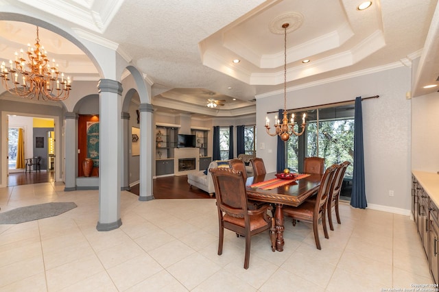 dining area featuring a healthy amount of sunlight, decorative columns, and a raised ceiling