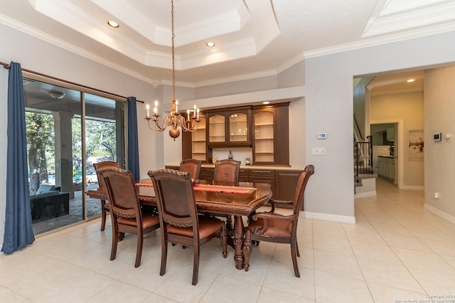 dining space with a tray ceiling, ornamental molding, a chandelier, baseboards, and stairs