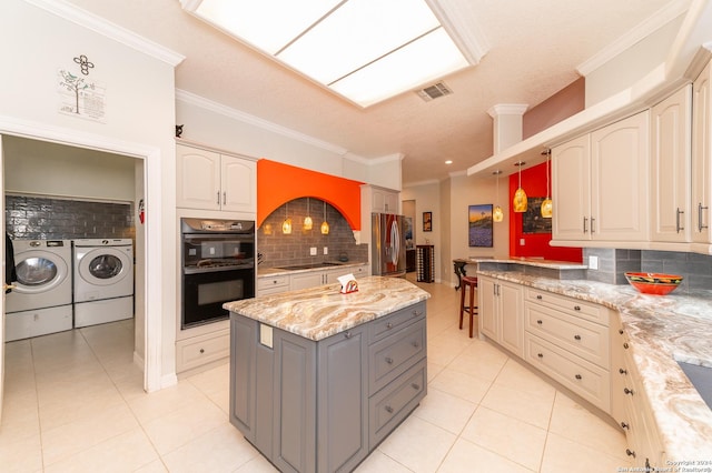 kitchen featuring light tile patterned flooring, visible vents, gray cabinets, black appliances, and washing machine and clothes dryer