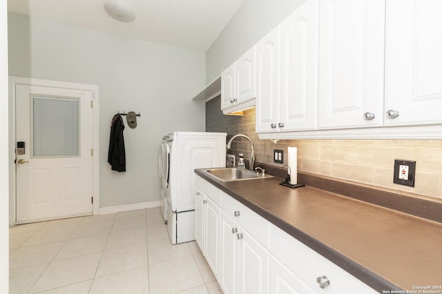 laundry room with light tile patterned floors, cabinet space, washing machine and dryer, a sink, and baseboards