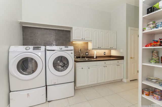 laundry room featuring light tile patterned floors, separate washer and dryer, a sink, and cabinet space