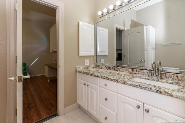 bathroom with double vanity, tile patterned flooring, baseboards, and a sink