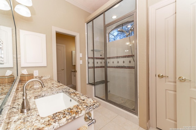 bathroom featuring double vanity, ornamental molding, a sink, a shower stall, and tile patterned floors