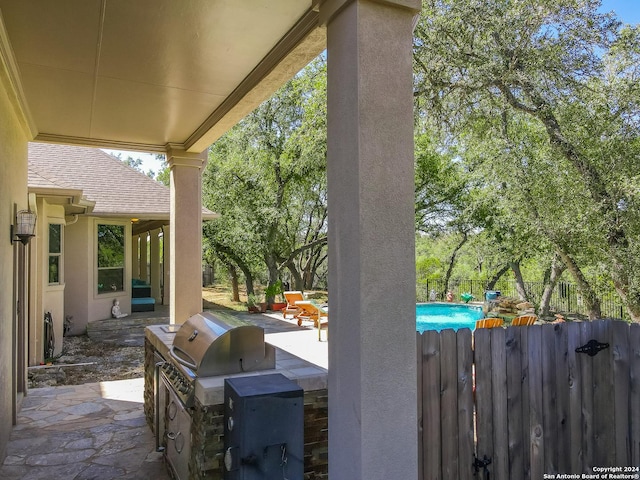 view of patio featuring exterior kitchen, fence, and a fenced in pool