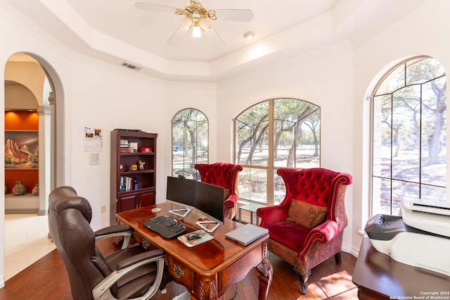 office featuring a tray ceiling, arched walkways, visible vents, a ceiling fan, and wood finished floors