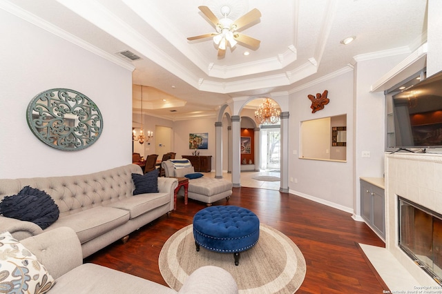 living area featuring arched walkways, a tray ceiling, wood finished floors, and a tile fireplace