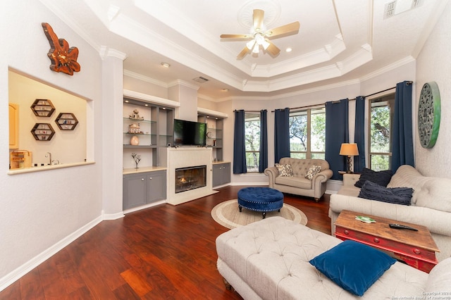 living area featuring a fireplace with flush hearth, a raised ceiling, visible vents, and wood finished floors