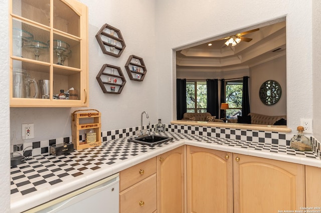 kitchen featuring tile countertops, a tray ceiling, crown molding, light brown cabinetry, and a sink