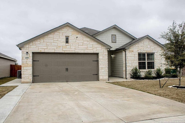 view of front of property featuring driveway, a garage, fence, and central AC unit