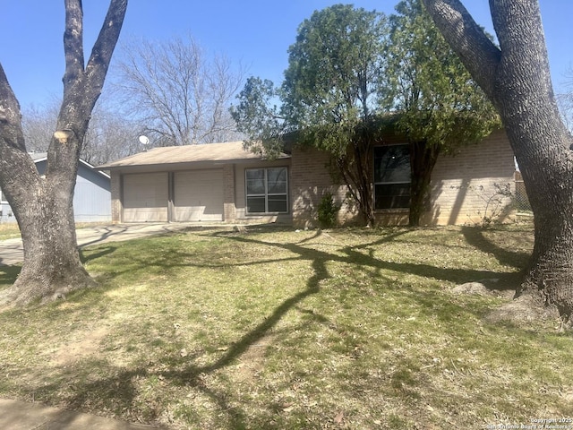 view of front of home with an attached garage, driveway, a front yard, and brick siding