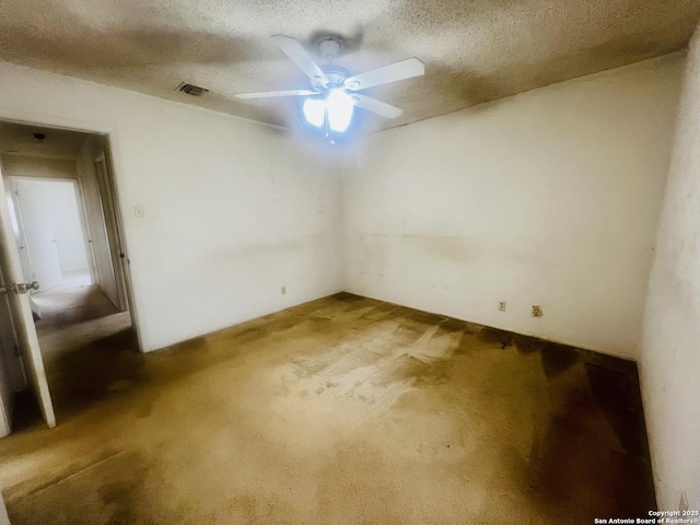 unfurnished room with carpet floors, visible vents, a textured ceiling, and a ceiling fan