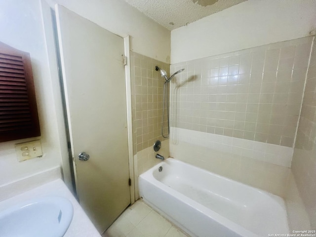 full bathroom with washtub / shower combination, a sink, a textured ceiling, and tile patterned floors