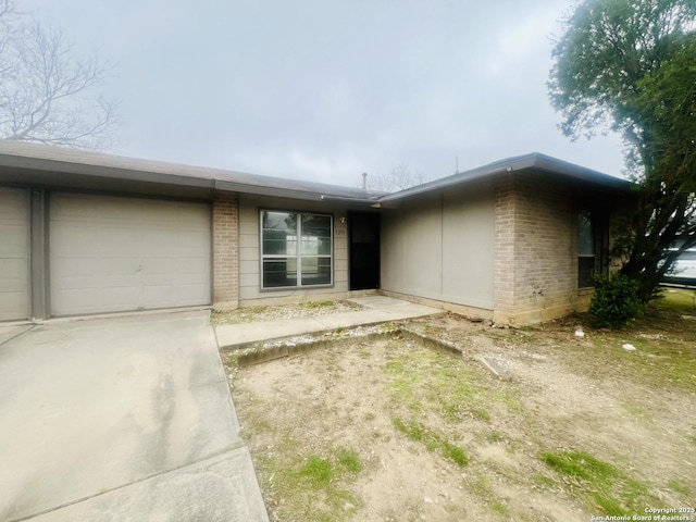 single story home featuring a garage, concrete driveway, and brick siding