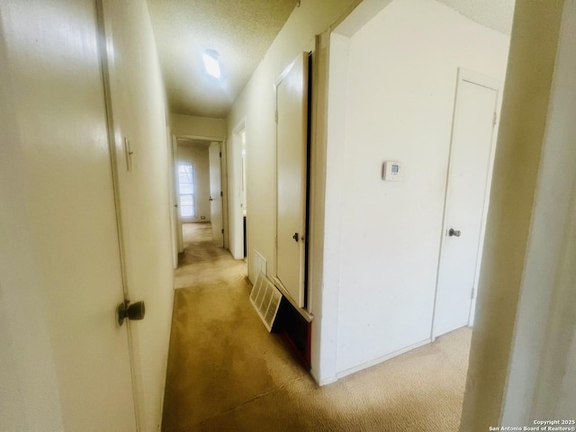 hallway featuring light colored carpet and visible vents