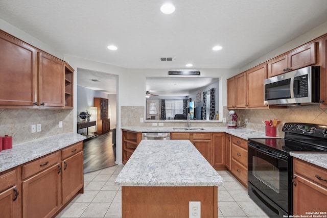 kitchen with light tile patterned floors, stainless steel appliances, a kitchen island, and visible vents