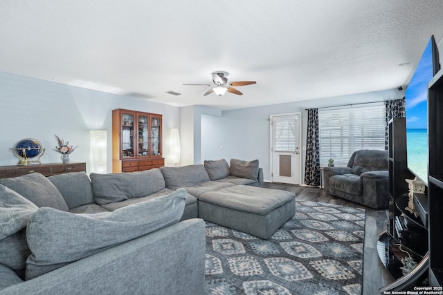 living area featuring visible vents, a textured ceiling, a ceiling fan, and wood finished floors