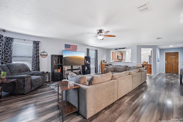 living room with dark wood-style floors, visible vents, ceiling fan, a textured ceiling, and baseboards