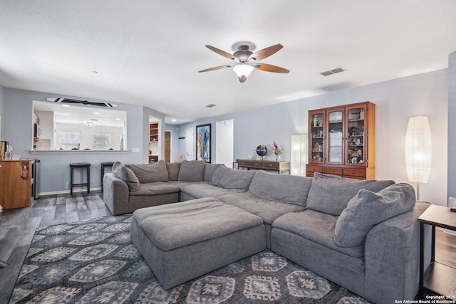 living area with a ceiling fan, visible vents, and wood finished floors